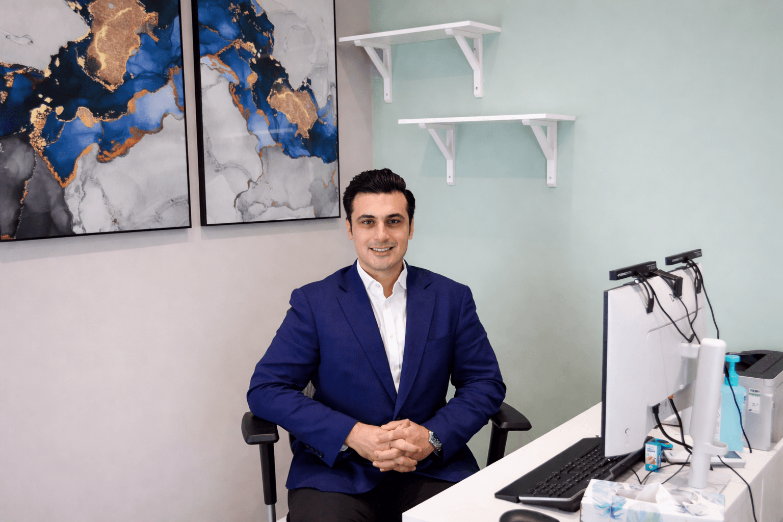 Dr. Shakil in suit seated at consultation desk